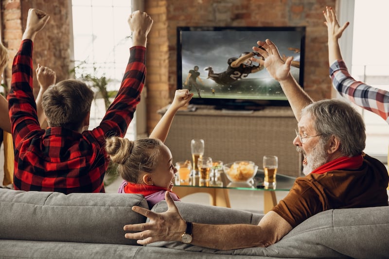 Family cheering for their favorite sports team, who they are watching on a NEXTGENTV in their...
