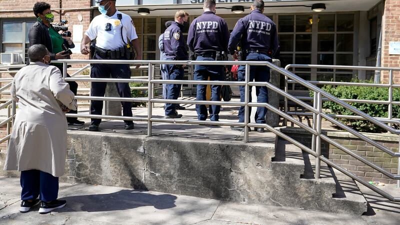 Police officers and community leaders stand outside the building where a man shot the mother...